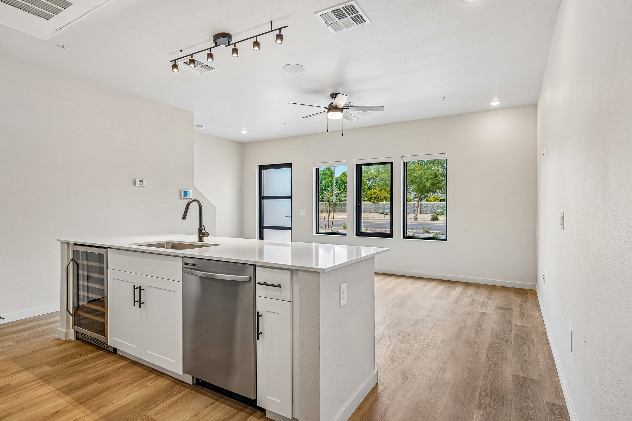 Contemporary kitchen with a large white island, wine fridge, and stainless steel appliances at Liberty at Estrella Falls in Goodyear, AZ.