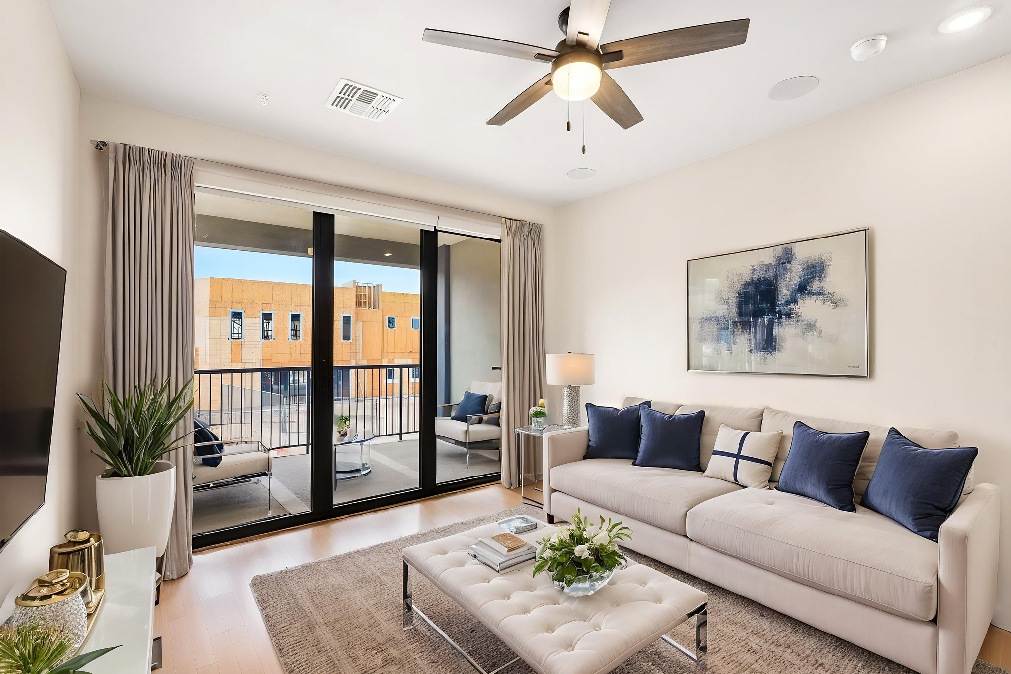 Living room featuring floor to ceiling accordion sliding doors, ceiling fan and seating, at Liberty at Estrella Falls in Goodyear, AZ.