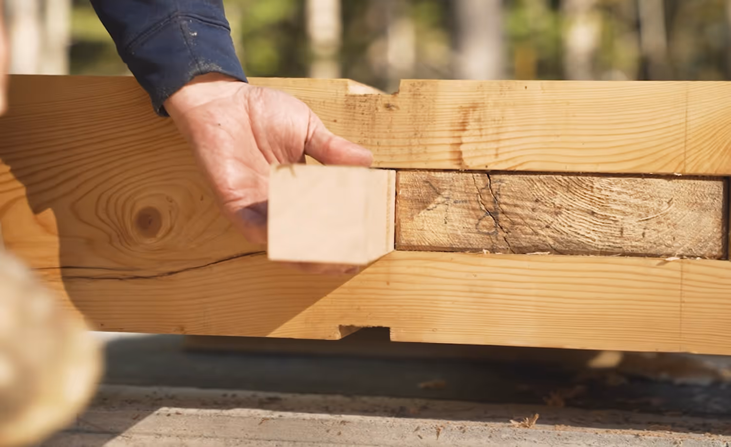 Hand fitting wooden block into precise joint during carpentry construction work