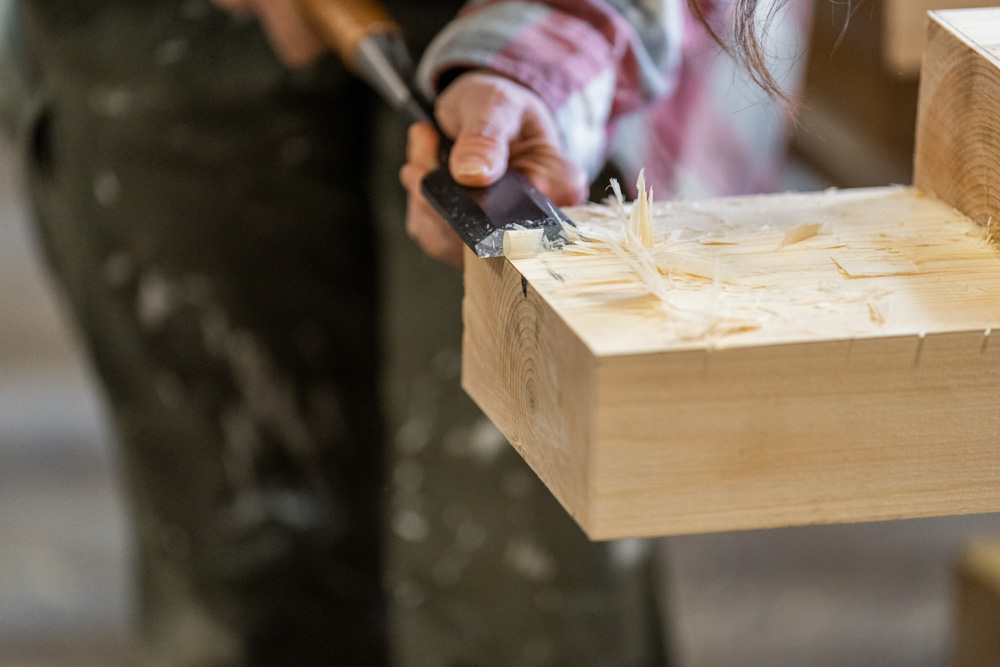 Woodworker using chisel to carve detailed design on wooden block