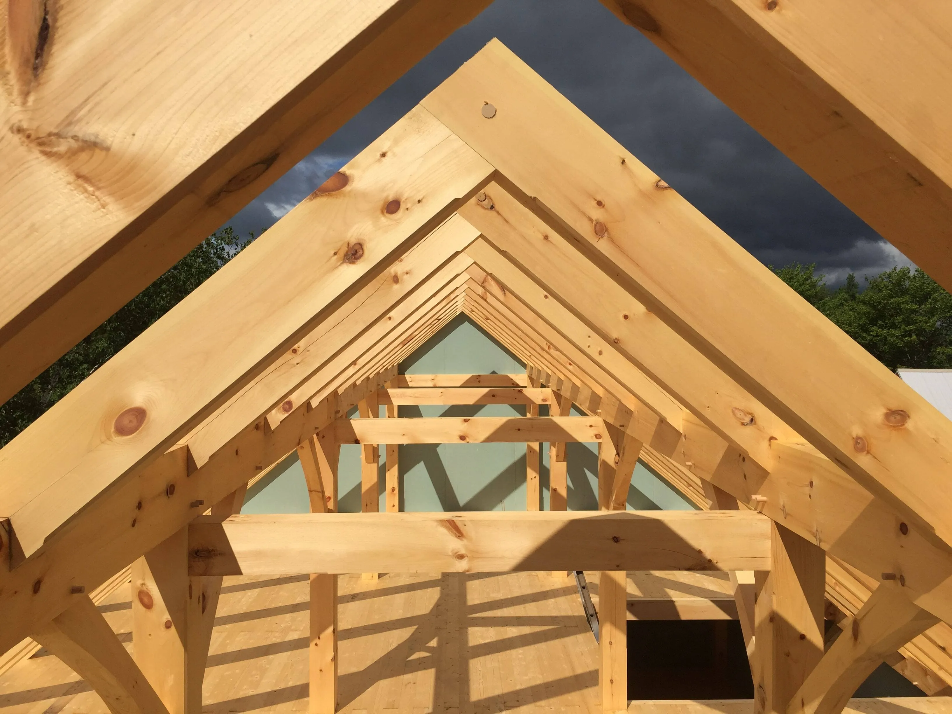 Interior view of wooden roof frame showing timber beams and sky beyond