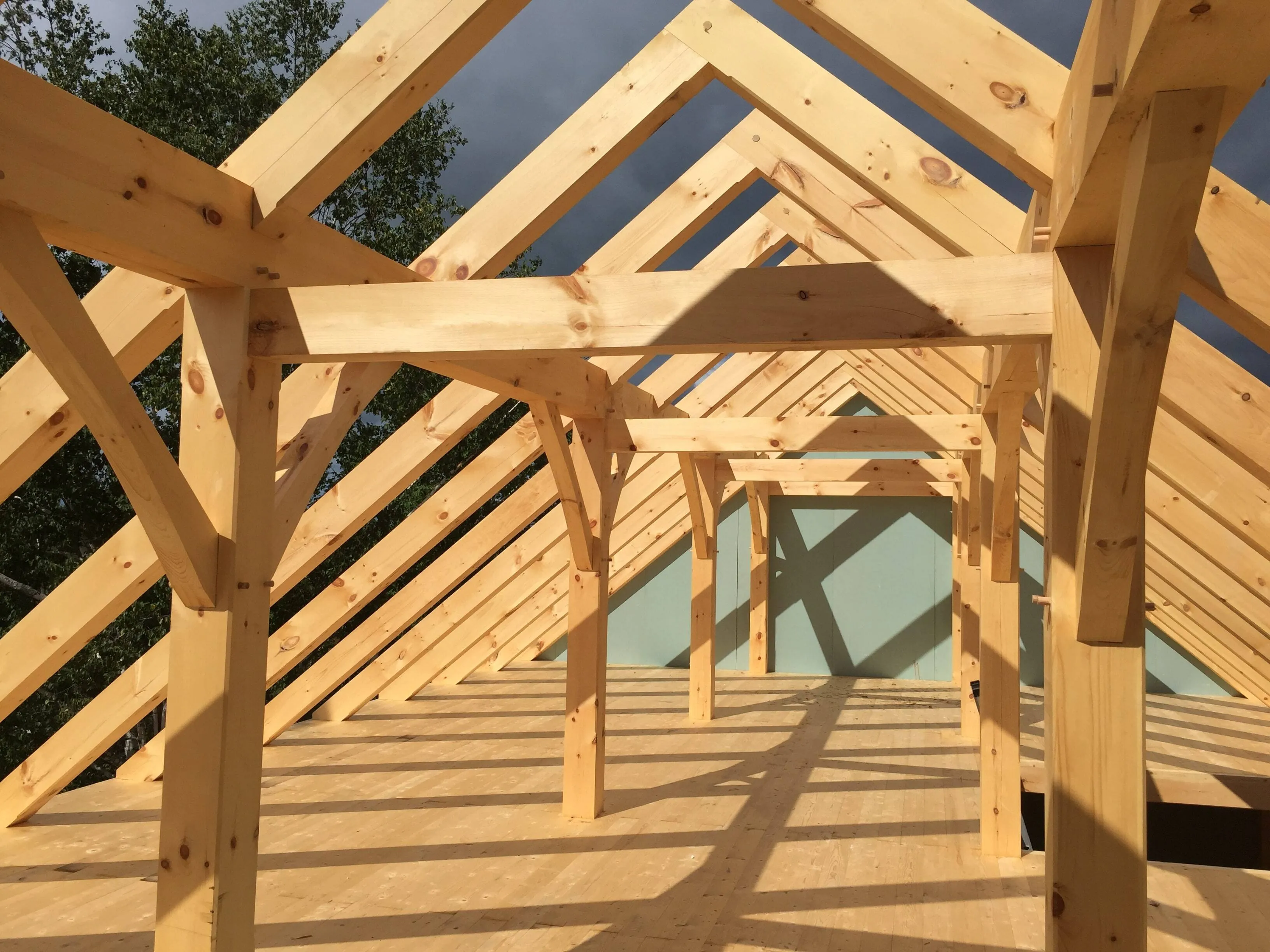 Interior view of wooden timber frame structure under construction with clear sky