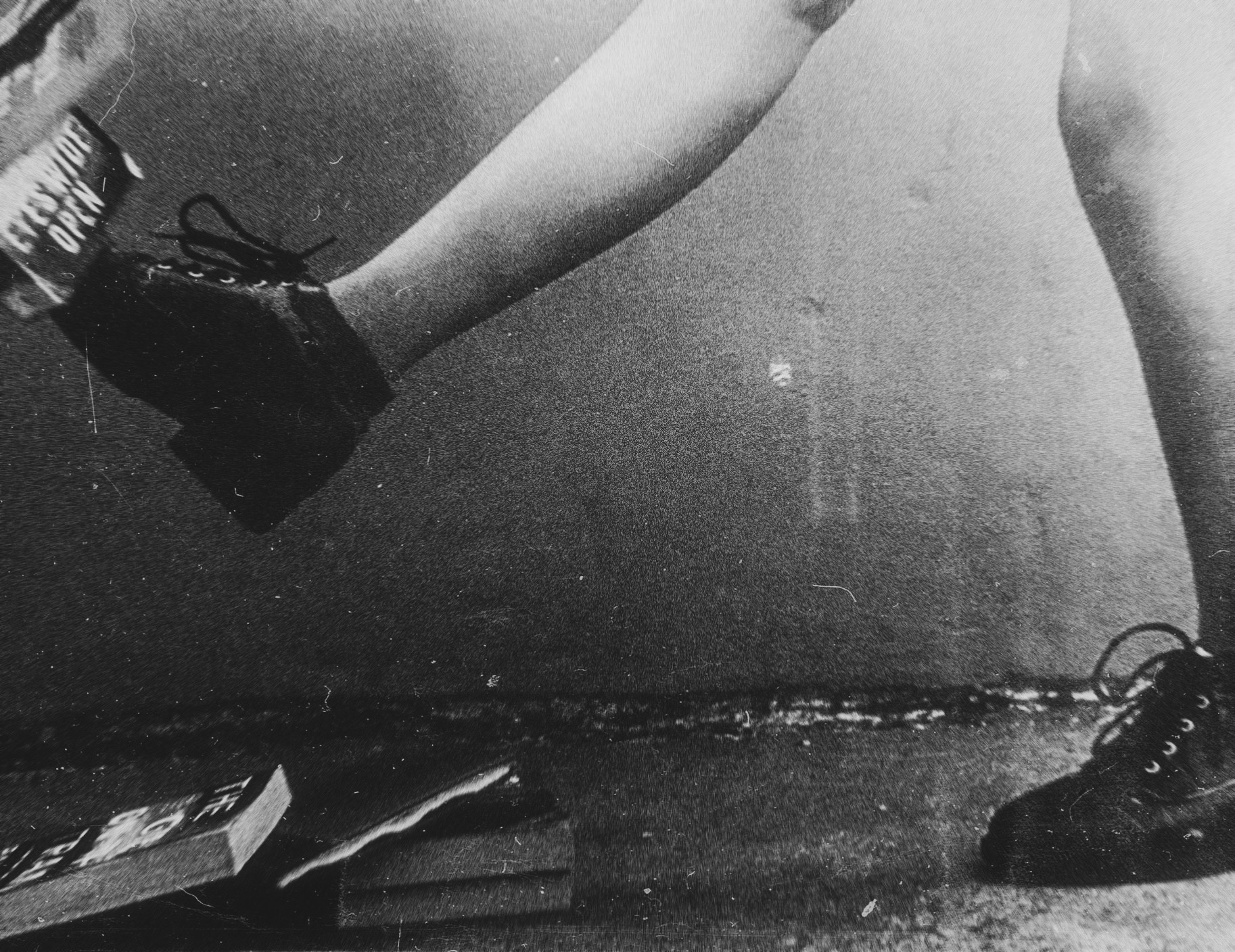 Black and white photo showing a person's bare legs kicking a stack of boots. The image shows a book frozen in motion, titled "Eyes Wide Open." 