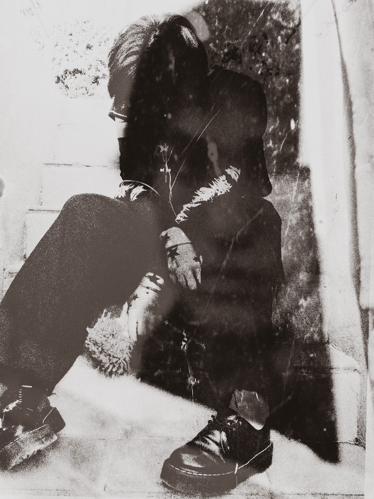 Black and white, grainy photograph of a person sitting on steps, head bowed, and hands clasped, with an overlay of a ghostly portrait