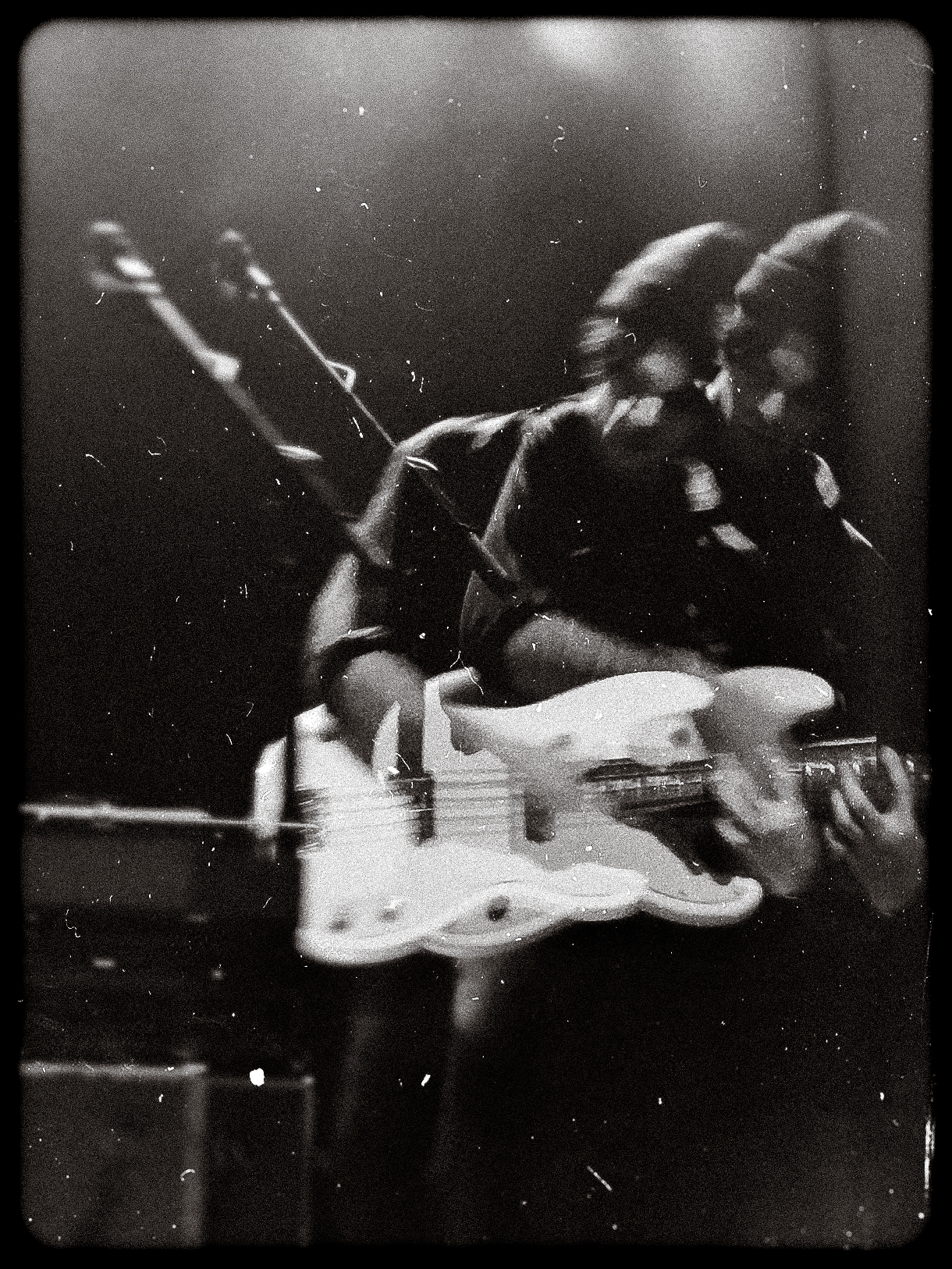 Black and white double exposure of a musician playing an electric guitar on stage.