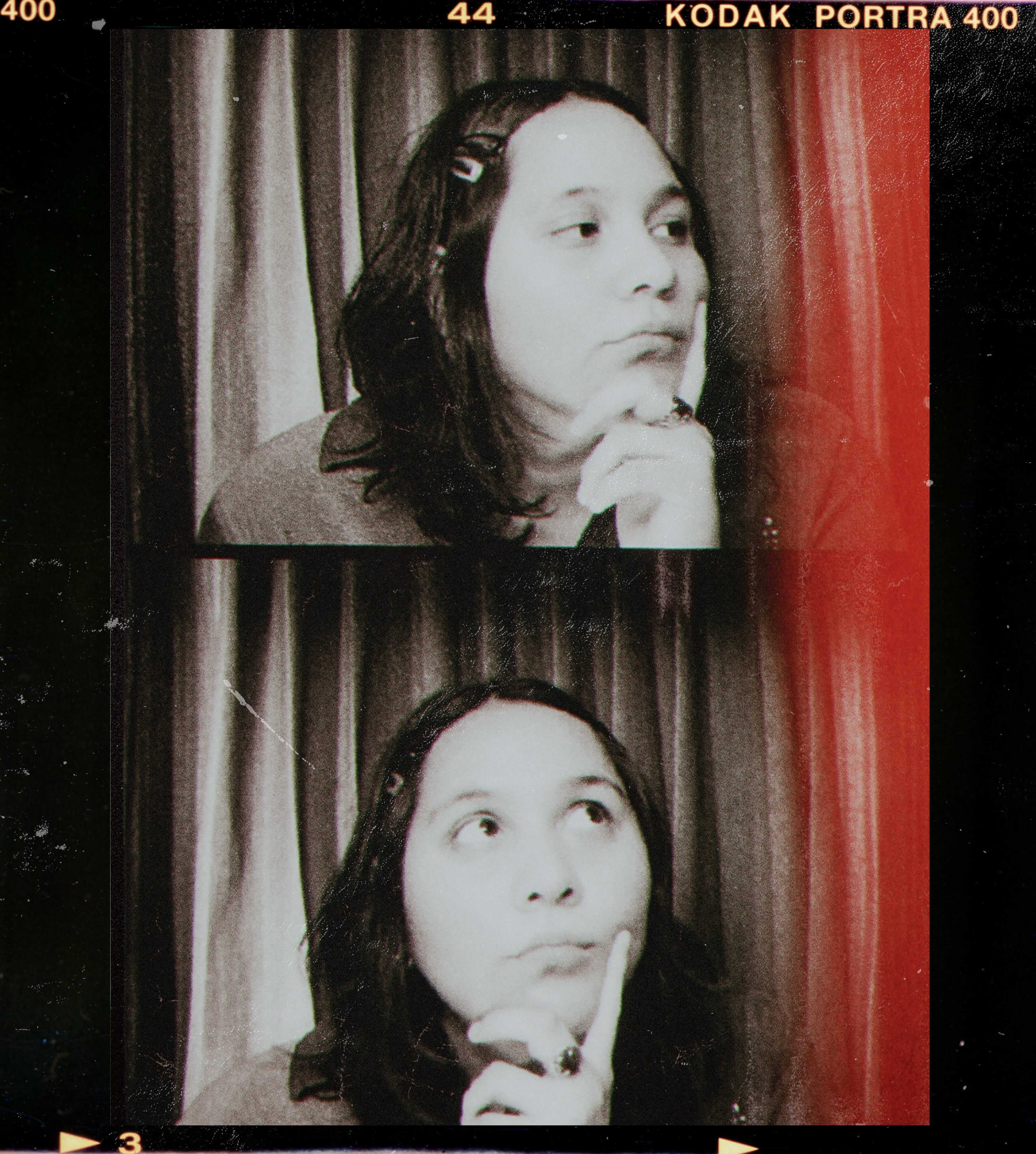 Black-and-white film strip style photo with two portraits of a person with shoulder-length hair, resting their chin on their hand, looking to the side and upward against a curtain background.