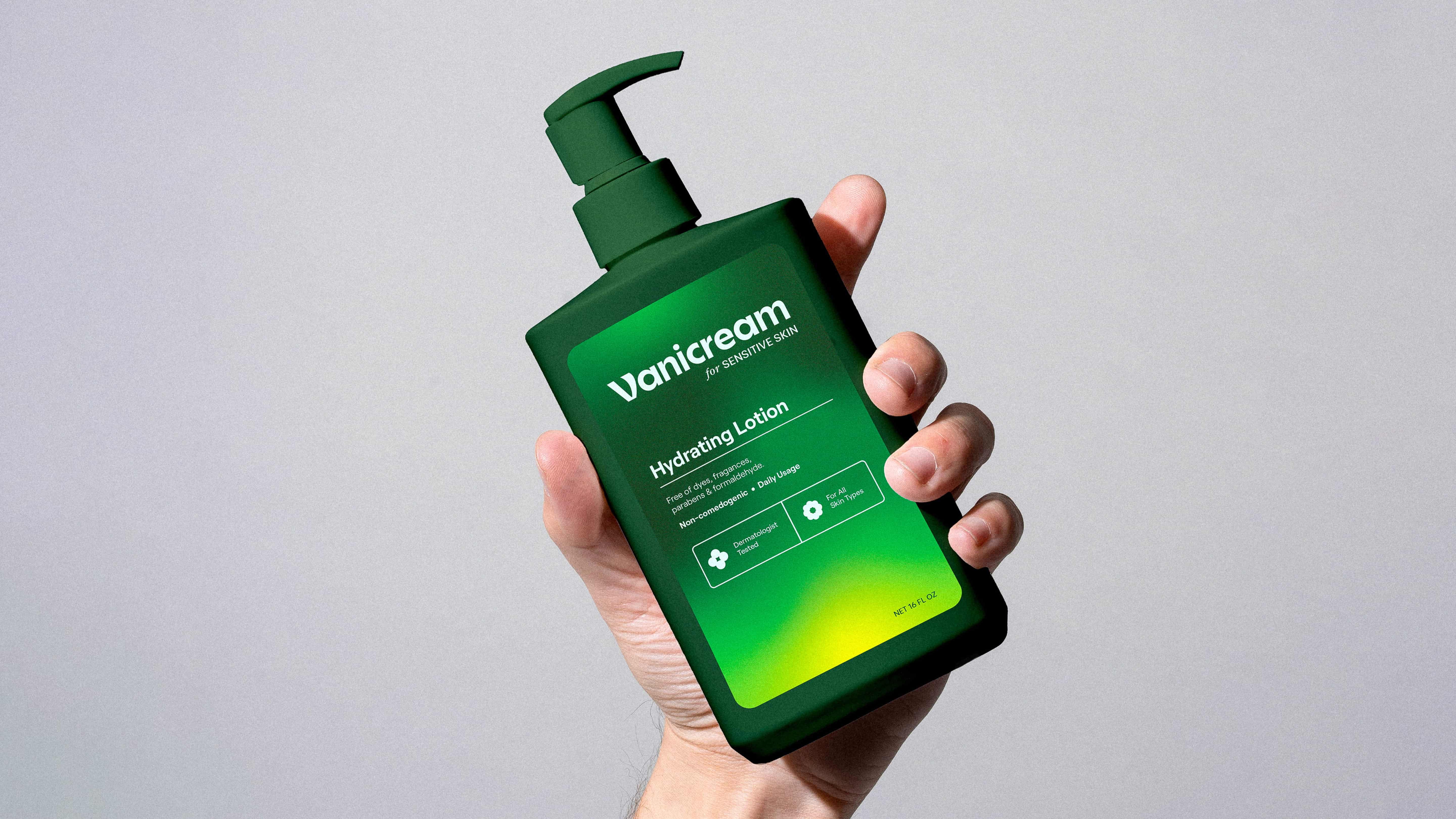Hand holding a green bottle of Vanicream hydrating lotion for sensitive skin against a gray background.