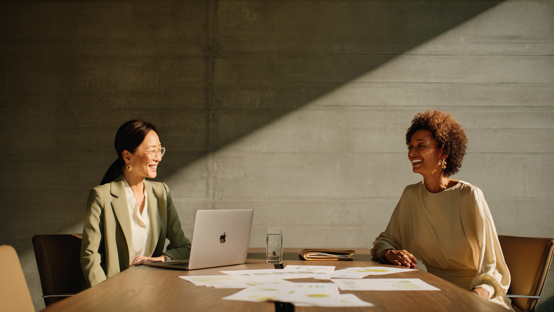 Two professional women in a bright office having a meeting and taking notes