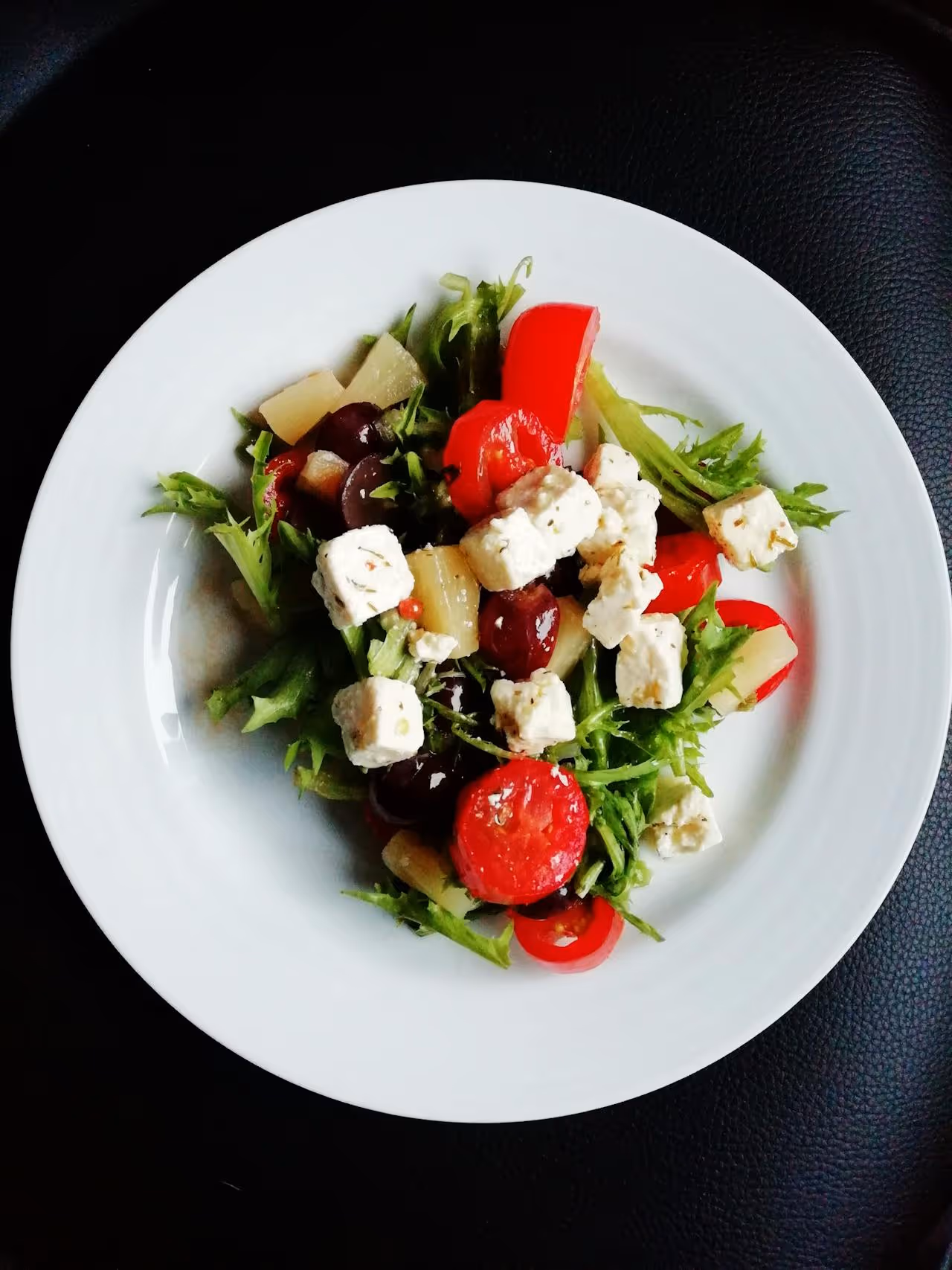 A white plate with a salad on it.
