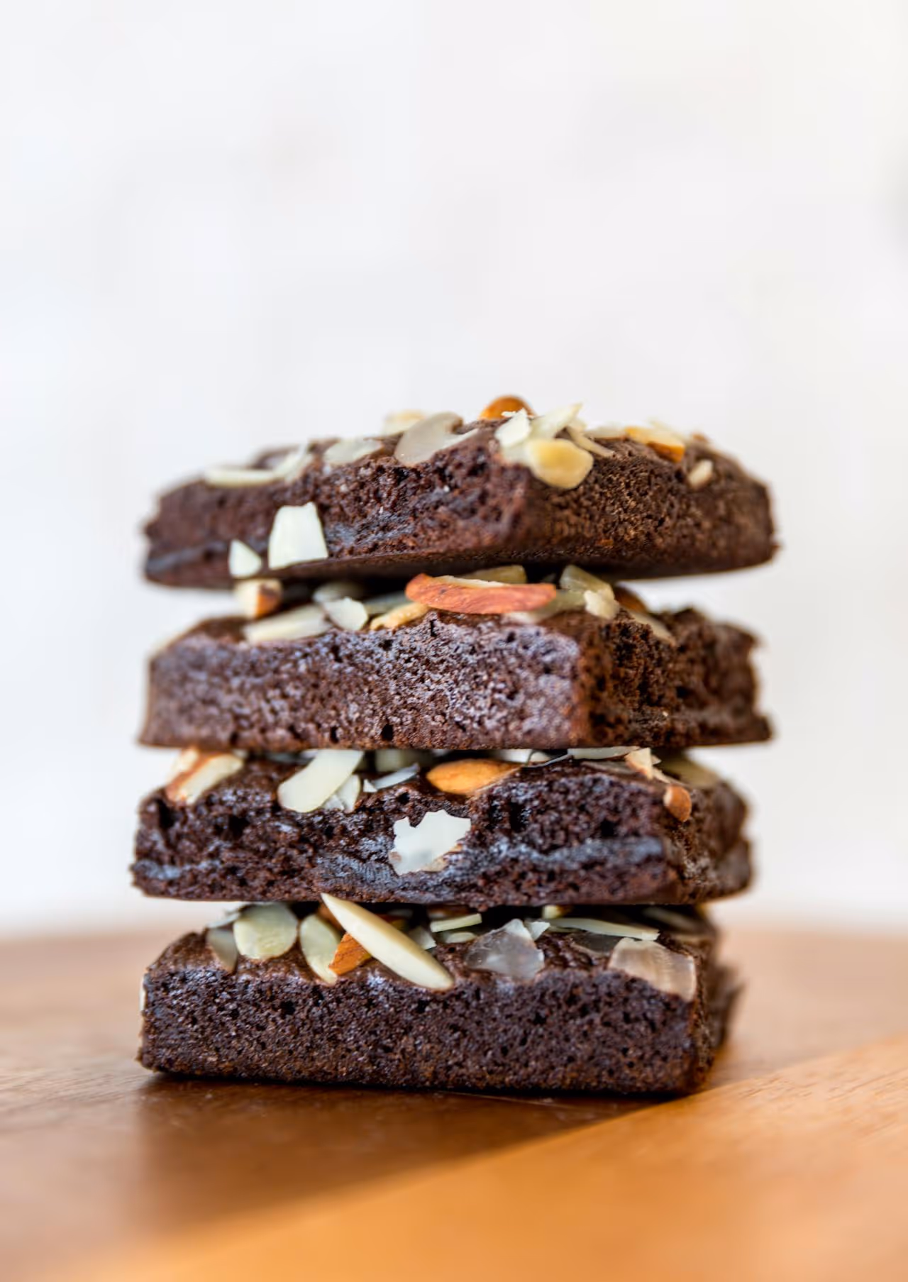 A stack of brownies with almonds and nuts on top.