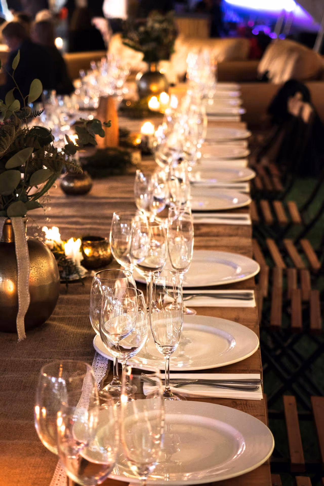 A table with a long row of wine glasses and plates.