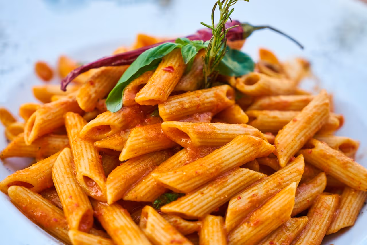 A plate of pasta with a pepper on top.