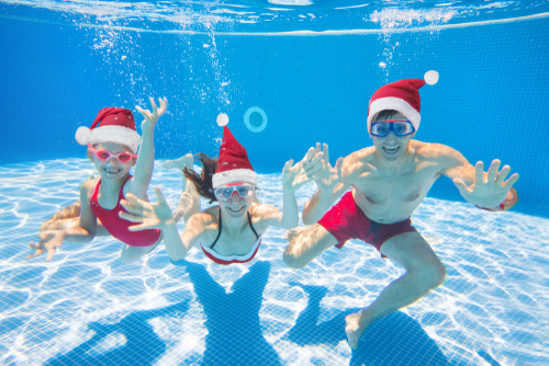 underwater photo of young family with kid in Santa hat in swimming pool
