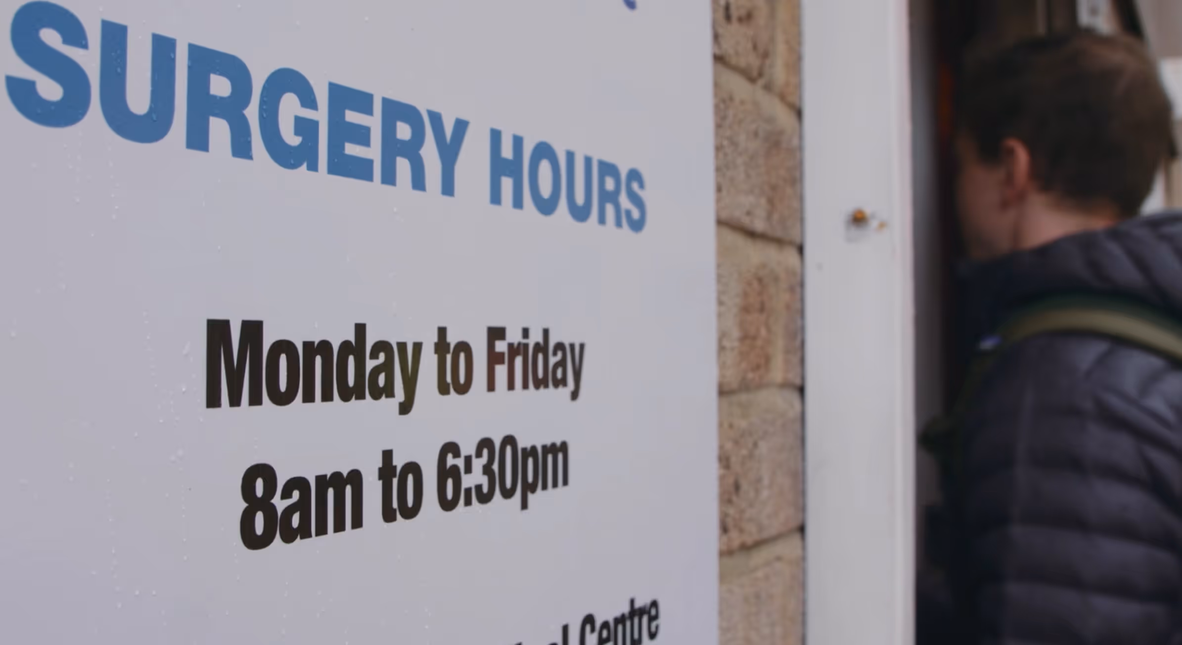 A GP practice with a sign showing its opening hours.