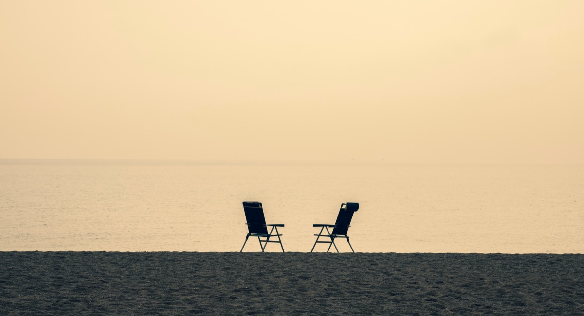 Two empty chairs side by side on an empty beach