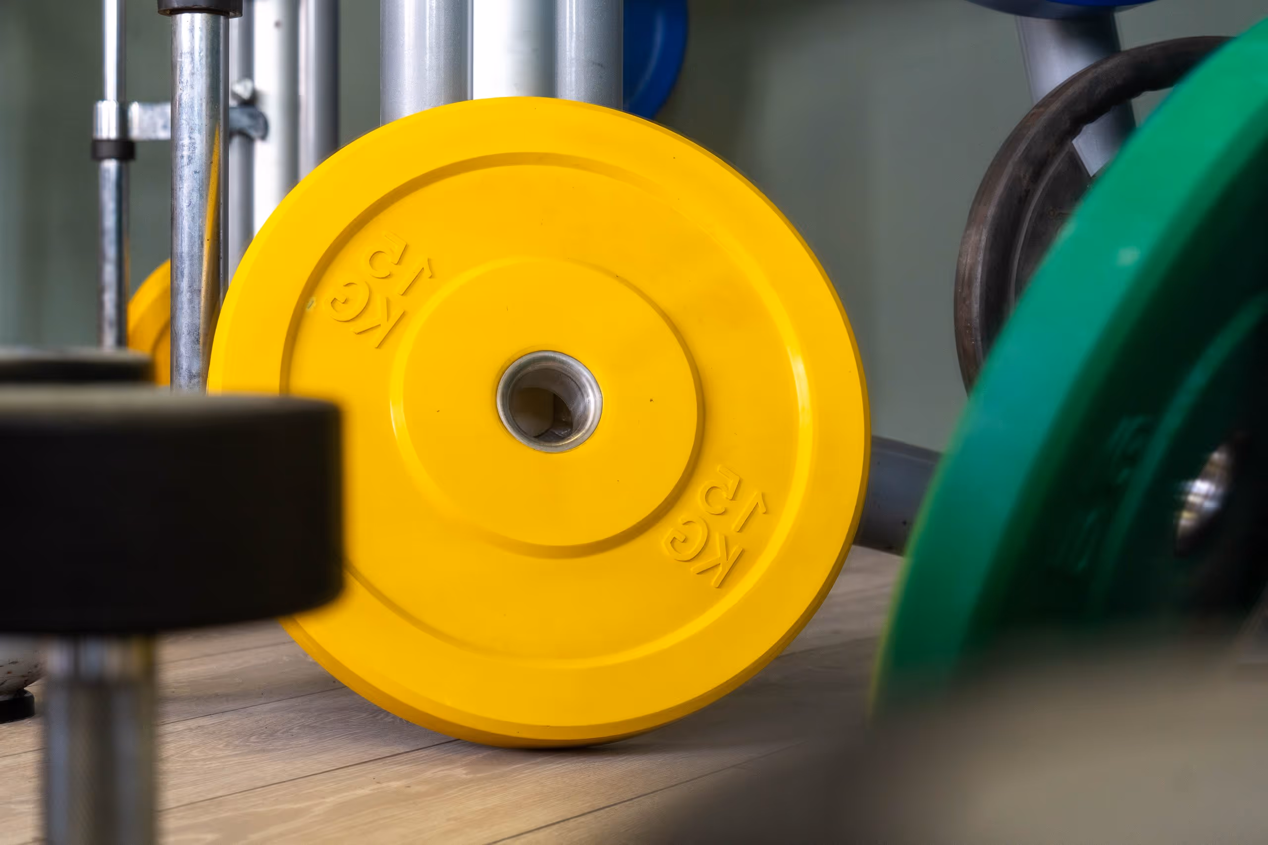 A closeup of assorted weights at Corespace Gym, a yellow weight plate and a green plate out of shot with a dumbell in the front out of focus