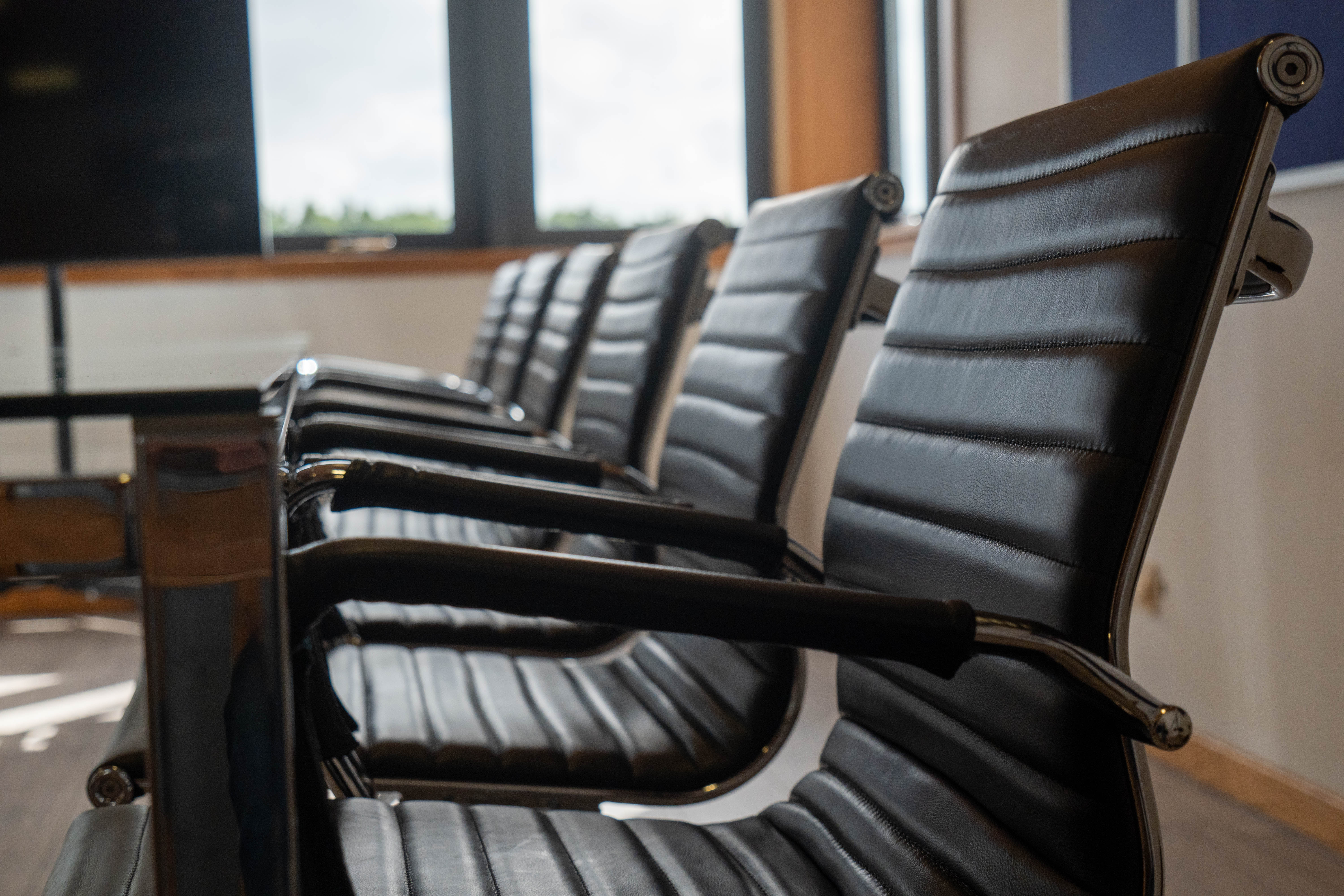 Closeup of modern chairs in a line around a table in a meeting room