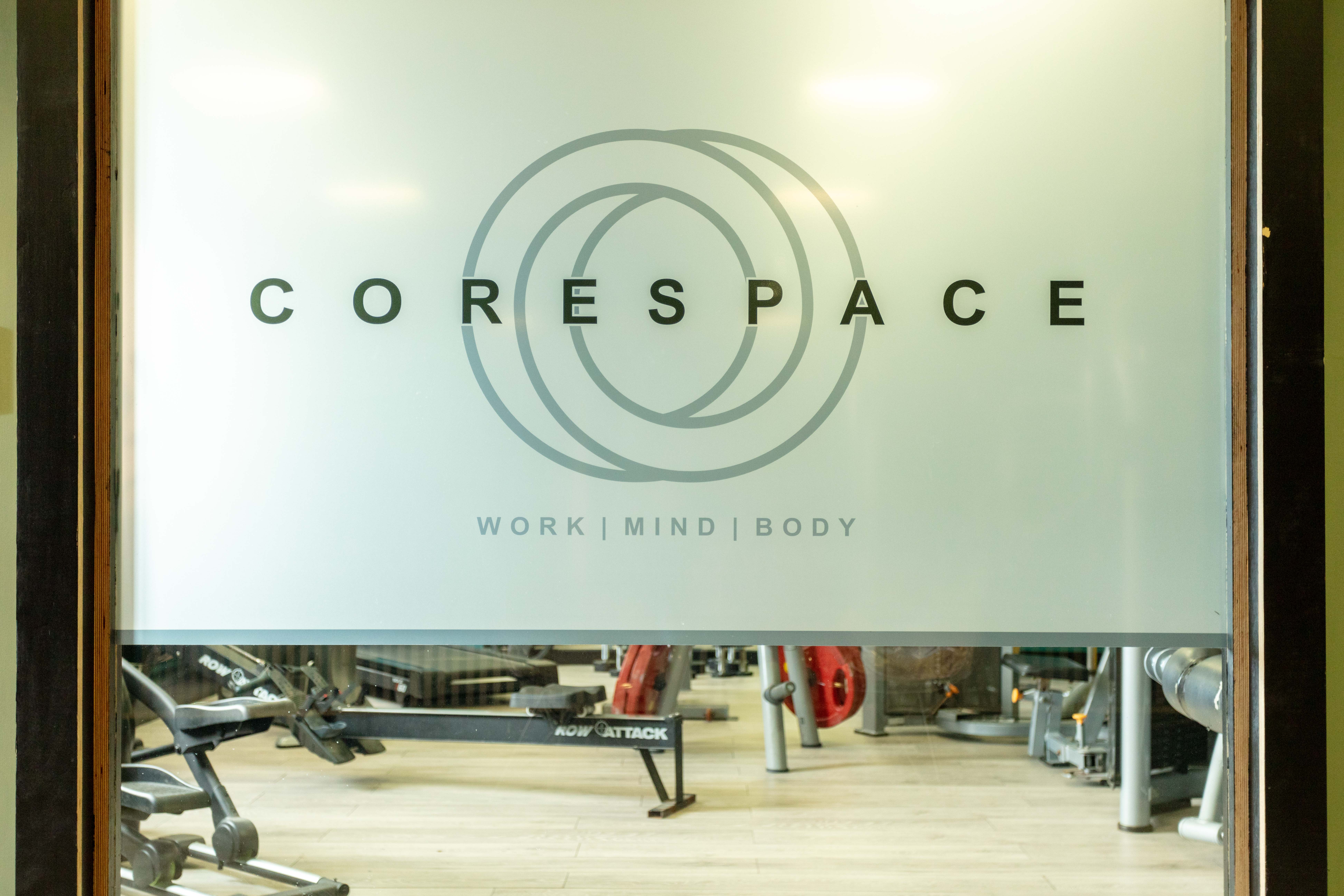 Closeup of the window of the gym at Corespace Kilwinning showing the logo with gym equipment in the background