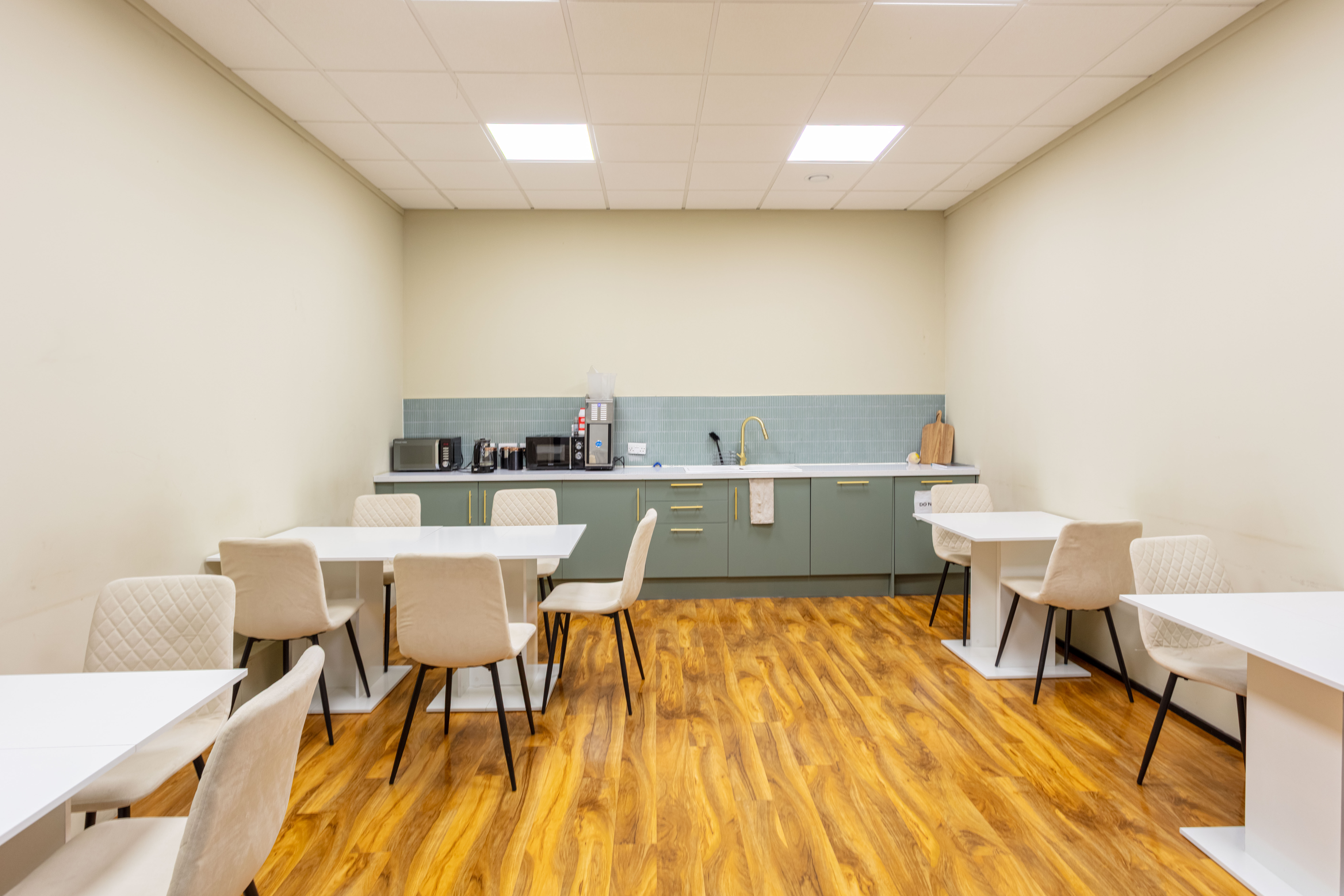 A modern green kitchen with white walls and furniture at Corespace Kilmarnock