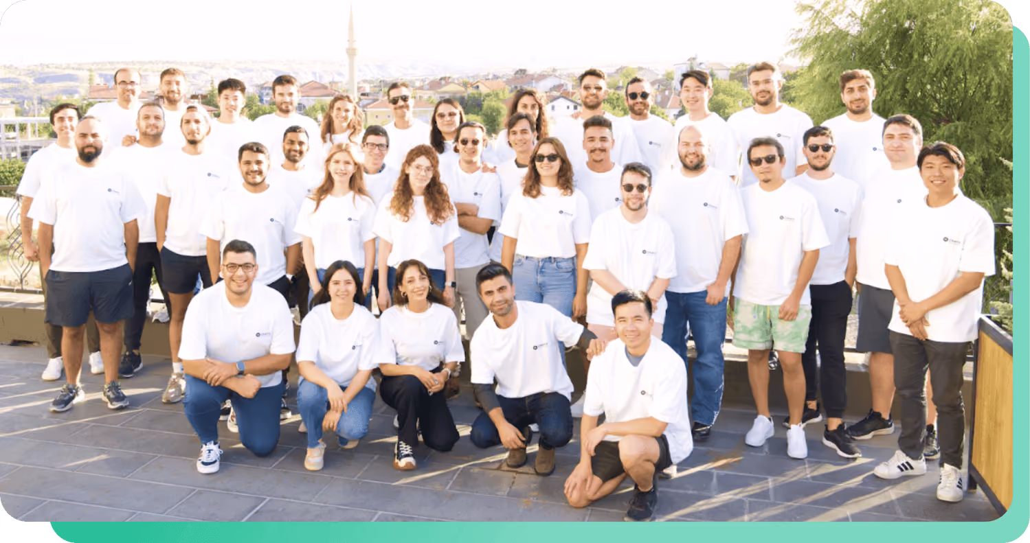 Group photo of about 35 men and women wearing white t-shirts outdoors on a sunny day.