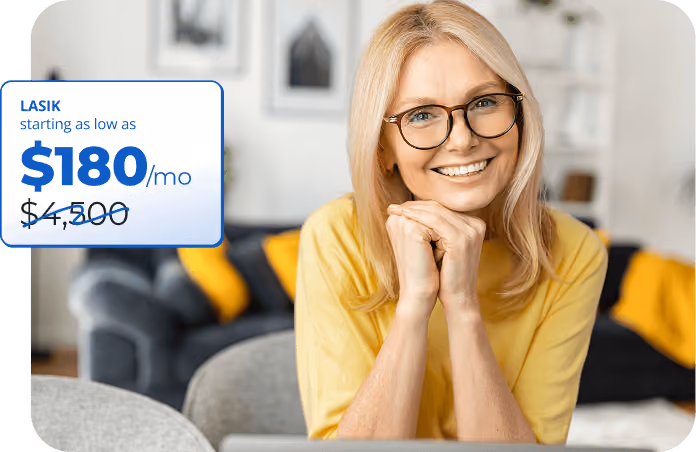 Smiling middle-aged woman wearing glasses and a yellow top sitting indoors with a blurred living room background, next to a promotional text box stating LASIK starting as low as $180 per month, with original price $4,300 crossed out.