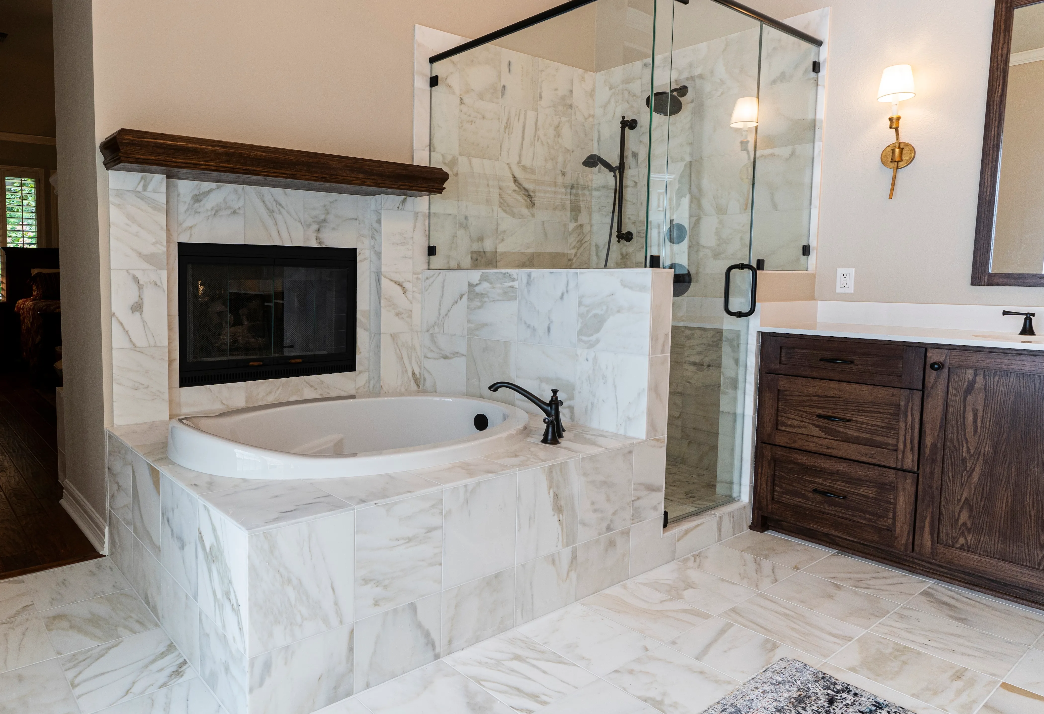 Remodeled bathroom with a marble soaking tub, glass walk-in shower, and dark wood vanity