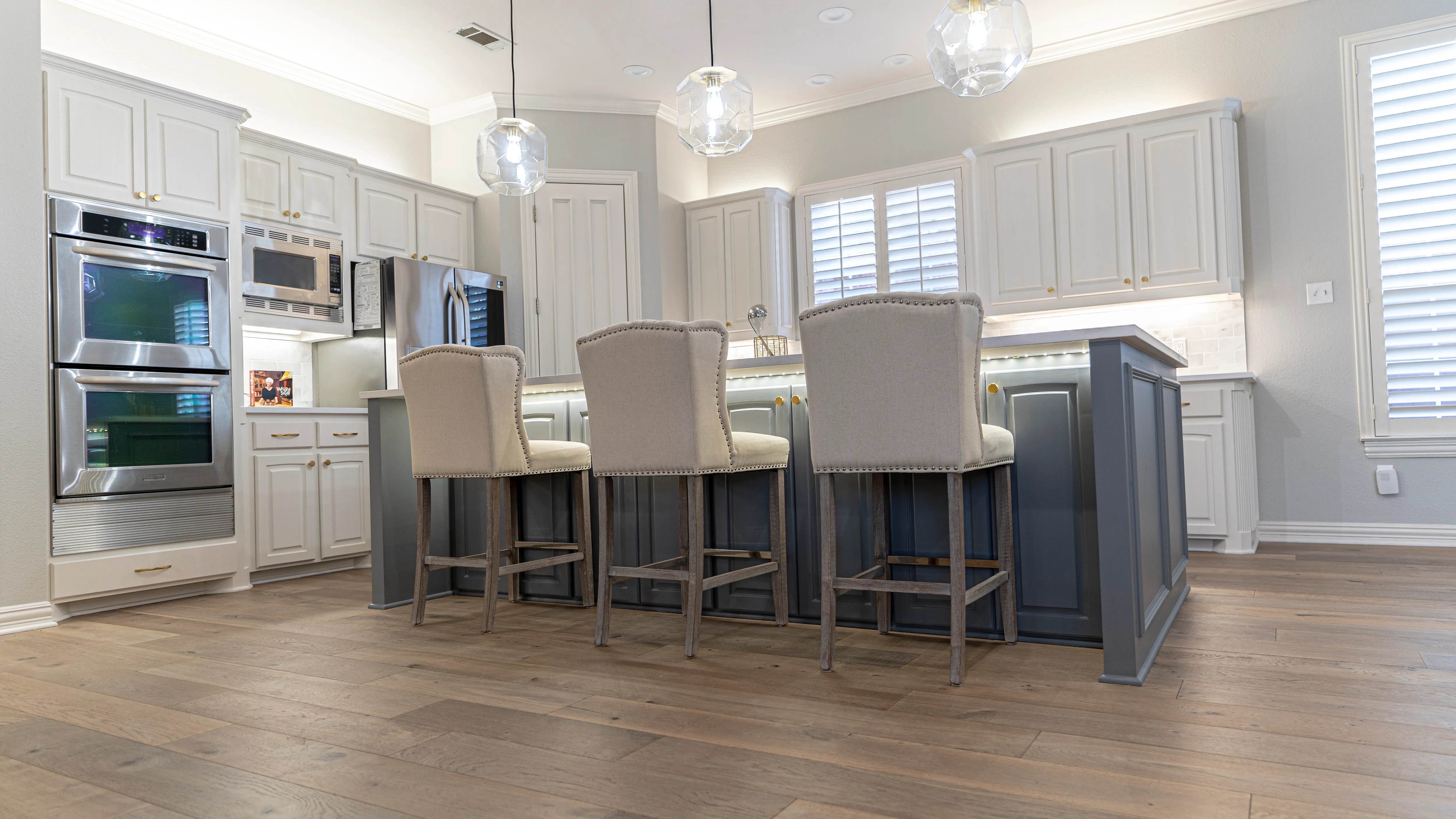 Remodeled gray-and-white kitchen with wood-look flooring and a large island