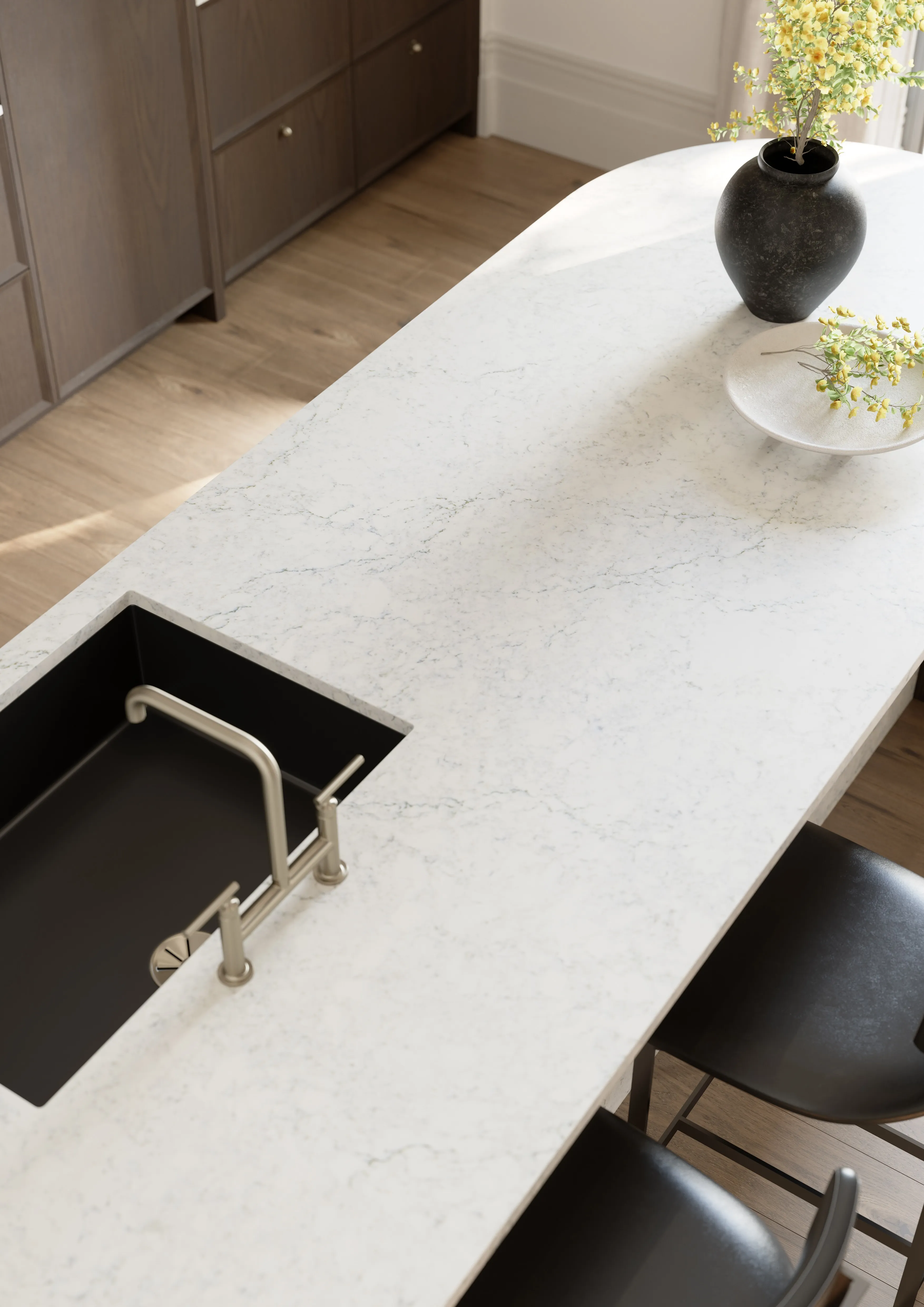 White quartz kitchen island with an undermount sink, black stools, and decorative vases
