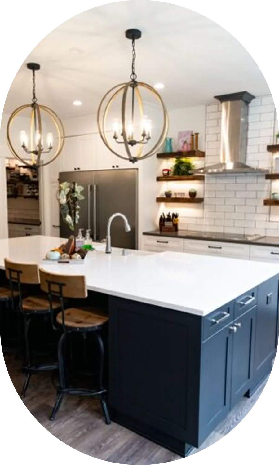Remodeled kitchen with a large white island, navy cabinetry, and globe pendant lights
