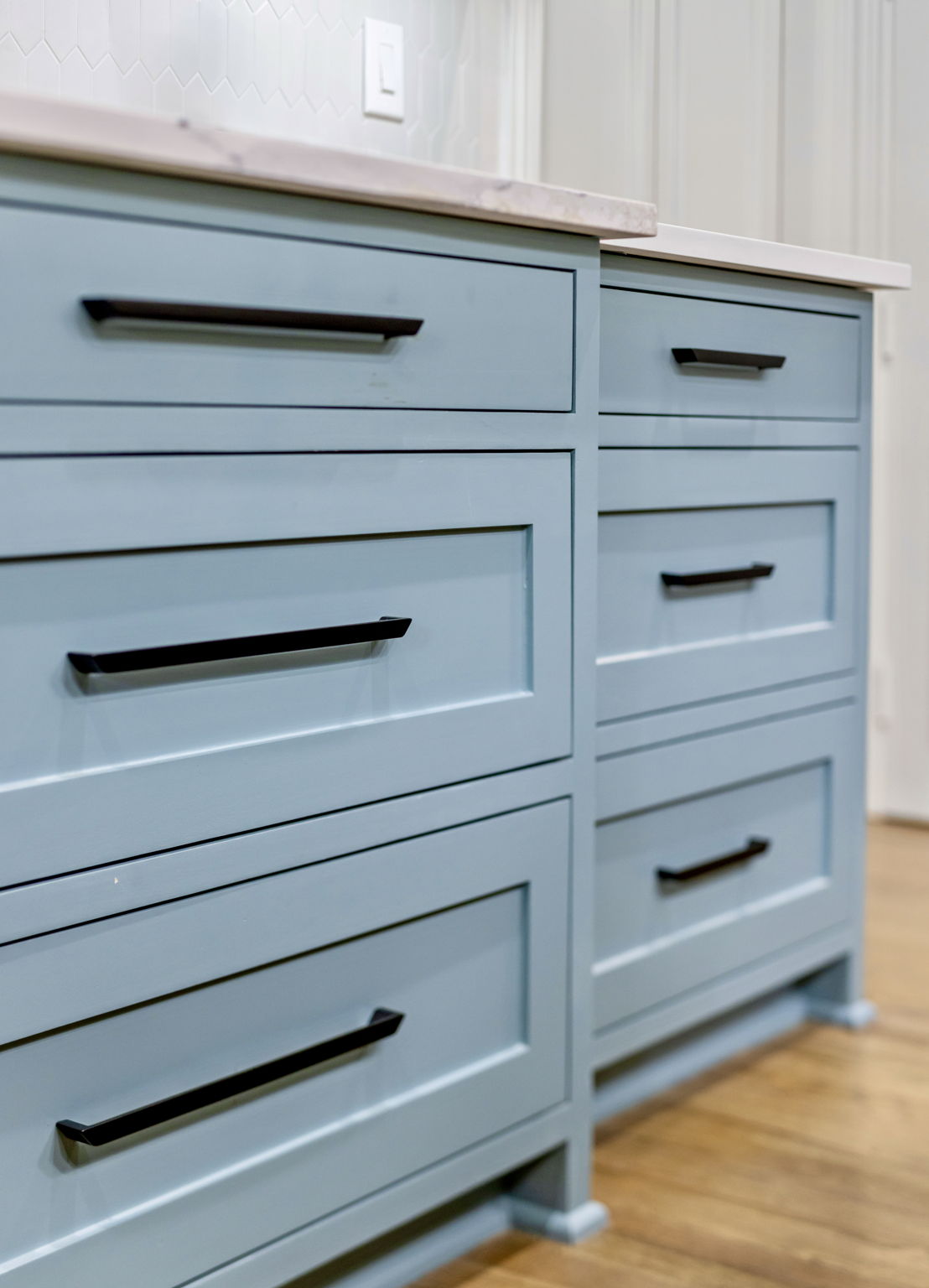 Blue vanity drawers with black bar handles and a light stone countertop.