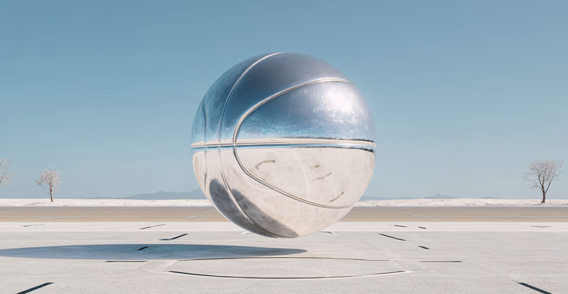 A shiny metallic basketball floating above a concrete surface under a clear blue sky.