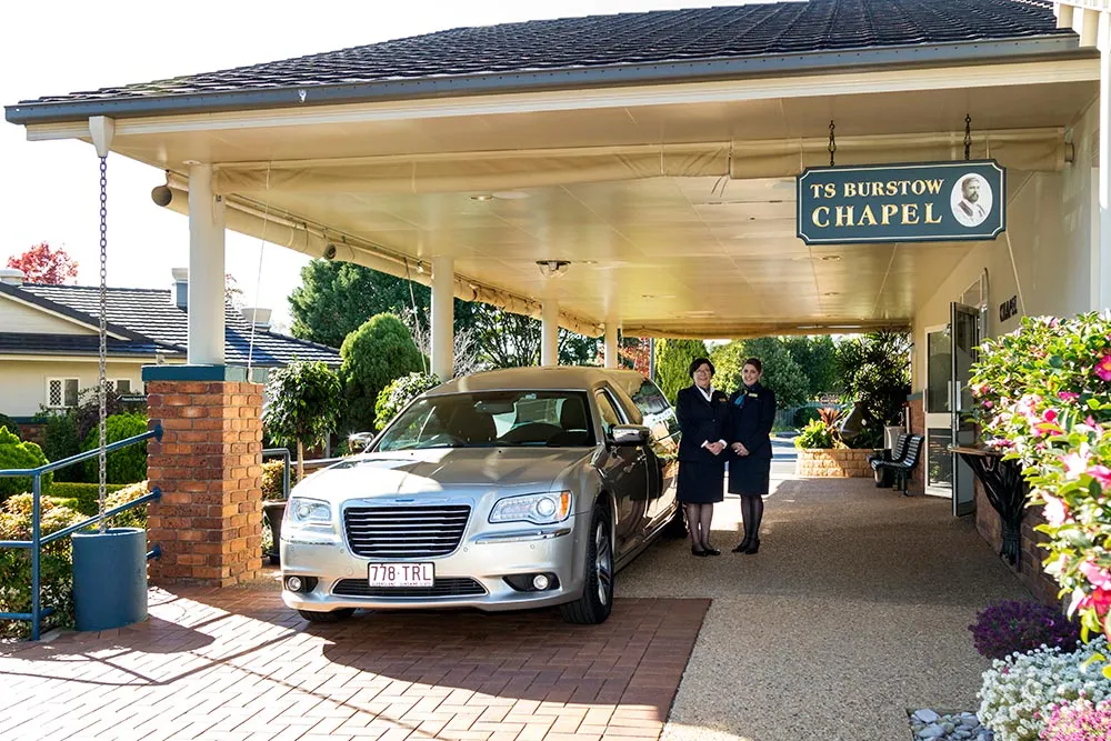 Hearse parked under a covered entrance at a funeral home.