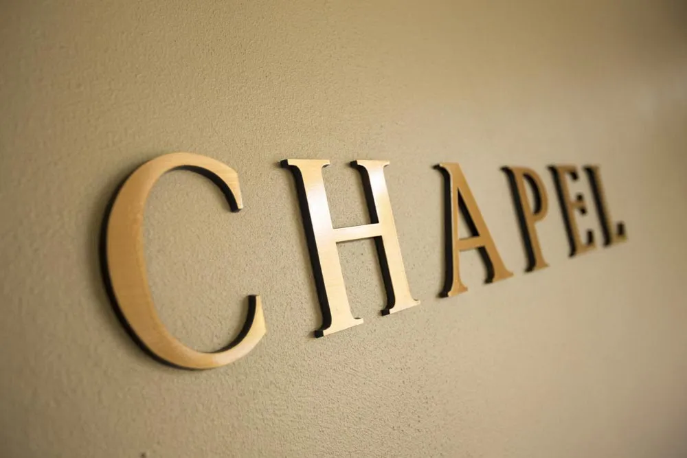 Close-up of a golden "CHAPEL" sign on a wall.