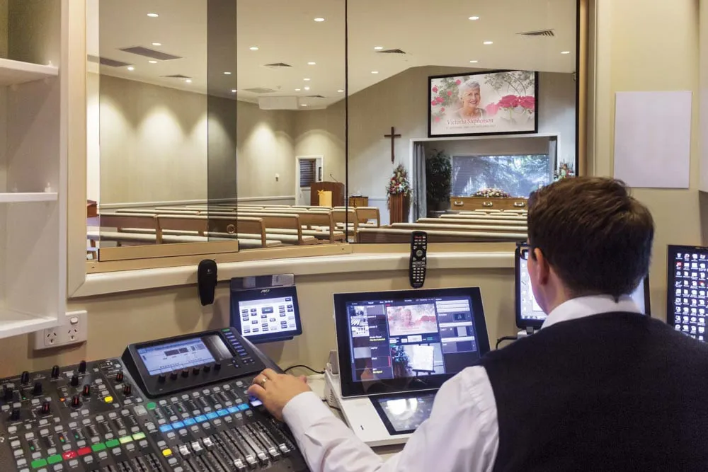 A man at an audio mixer in a control room.