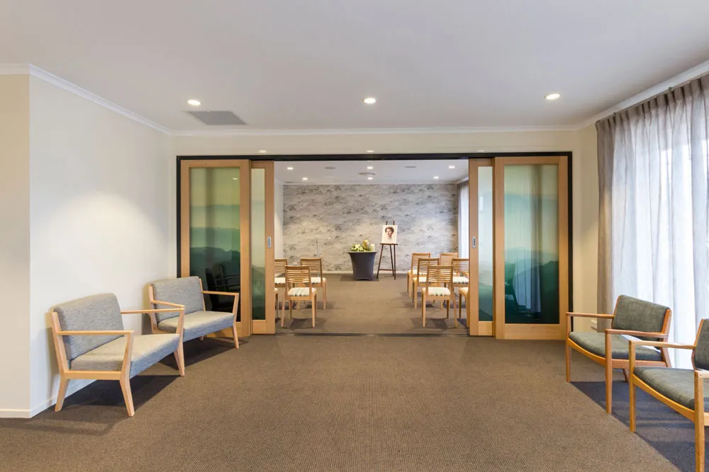 Viewing room with seating, and a portrait on an easel.