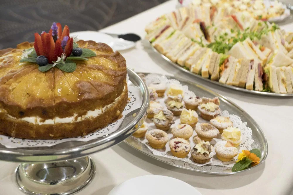 Dessert table with cake, pastries, and sandwiches.