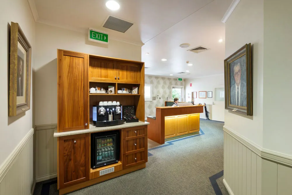 Bright foyer with a coffee station, reception desk, and exit sign.
