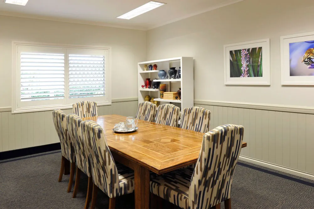 Conference room with large table, patterned chairs, and art.
