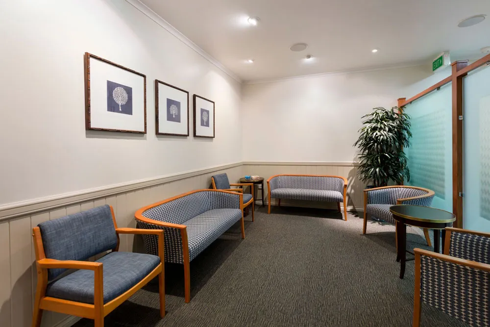 Waiting room with various seating, artwork, and a plant.