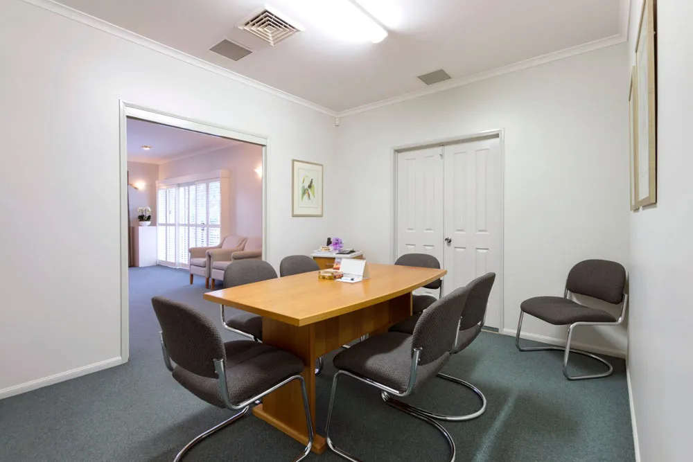Meeting room with table and chairs, adjacent to another space.