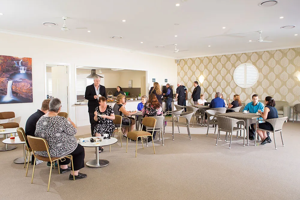 People gather in a bright, spacious room with a kitchenette.