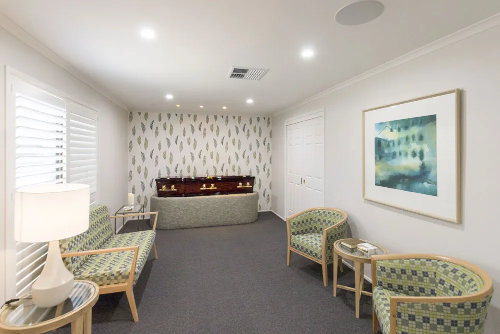 Viewing room with green chairs, artwork, and ample seating.