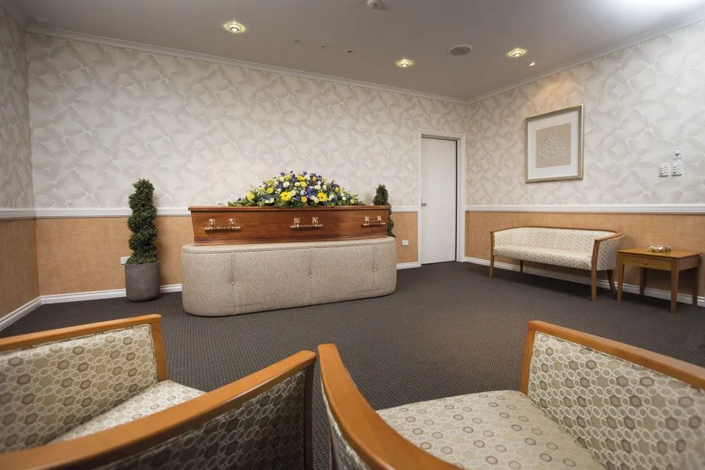 Spacious viewing room with casket, seating, and side tables.