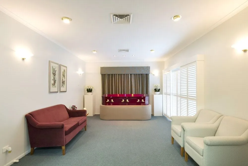 Bright, empty funeral home hallway with red and white sofas.