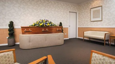 A modern funeral room with a casket and seating.