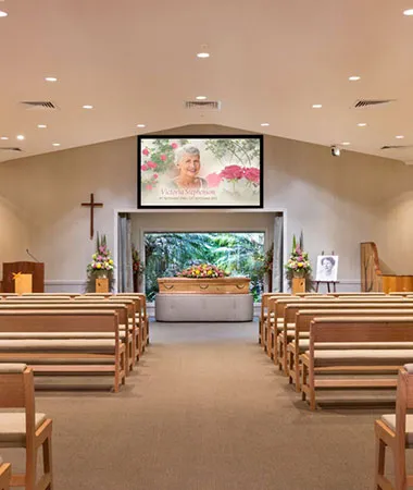 Funeral chapel with casket and large screen displaying photo.