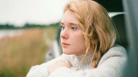 A young woman with blonde hair looking out a car window.