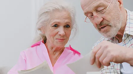 An elderly couple looks through old photographs together.