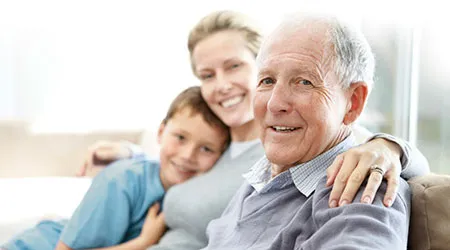 A multi-generational family (grandfather, mother, son) smiling together.