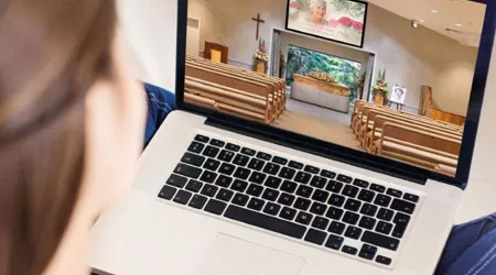 A person views a live-streamed funeral service on a laptop.